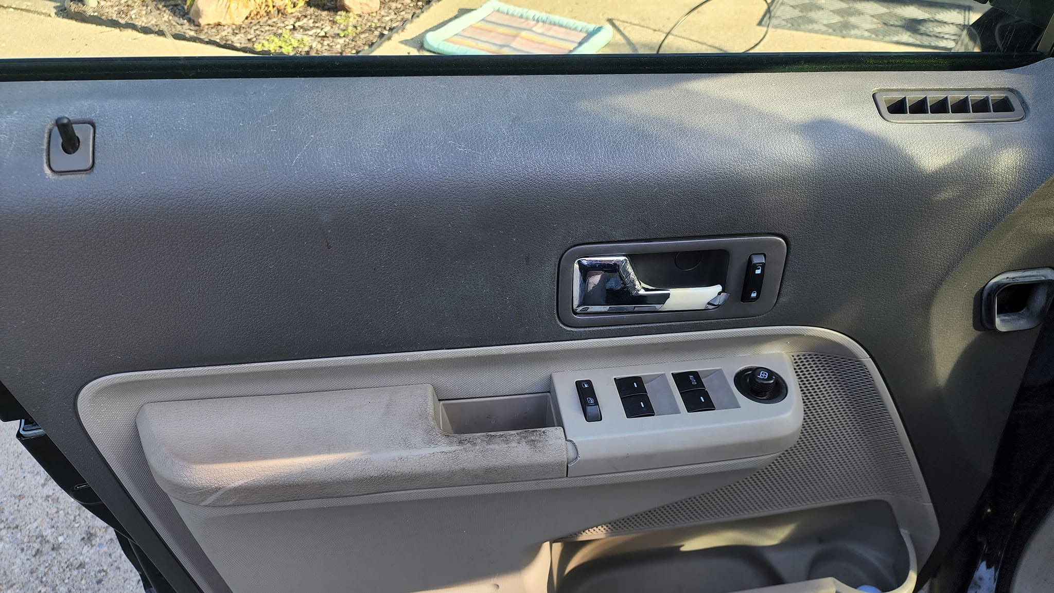 Vehicle door panel before interior detailing, with visible dirt and wear marks